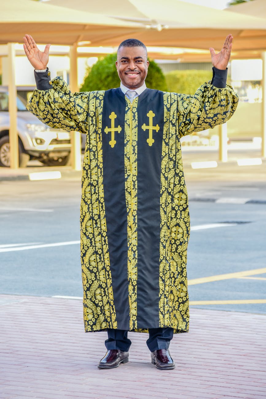 man in blue and yellow floral long sleeve shirt standing on road